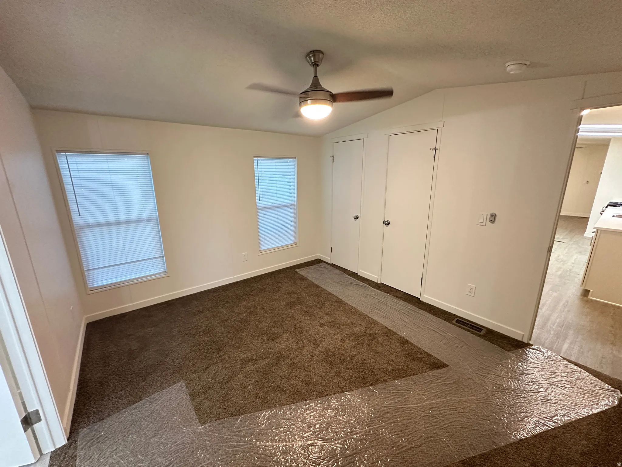 Bedroom with two windows, a ceiling fan with light fixture, and two doors