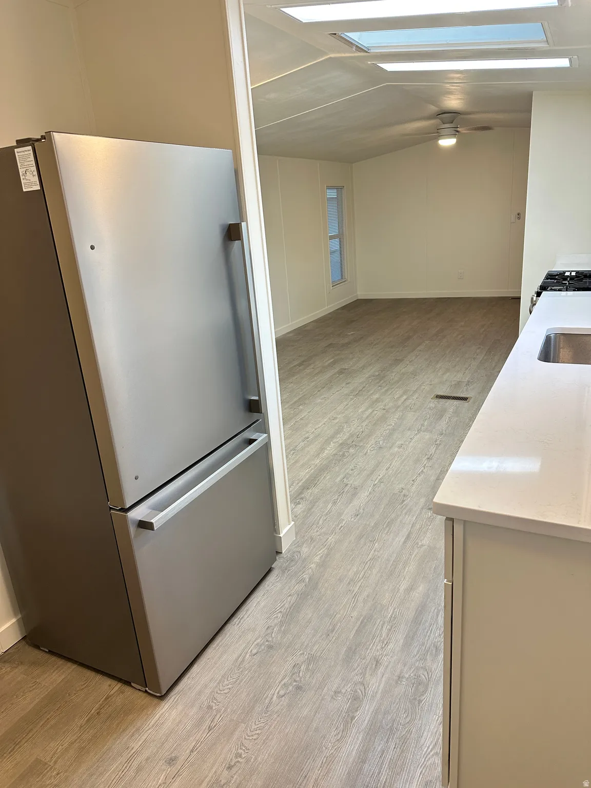 Modern kitchen featuring a stainless steel refrigerator, light-toned countertops, and a built-in sink