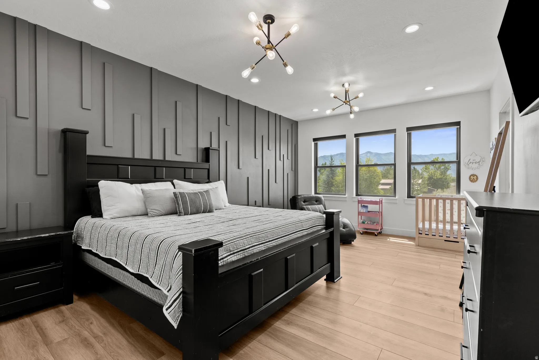 Spacious room featuring a textured accent wall, light wood-finish flooring, and multiple windows