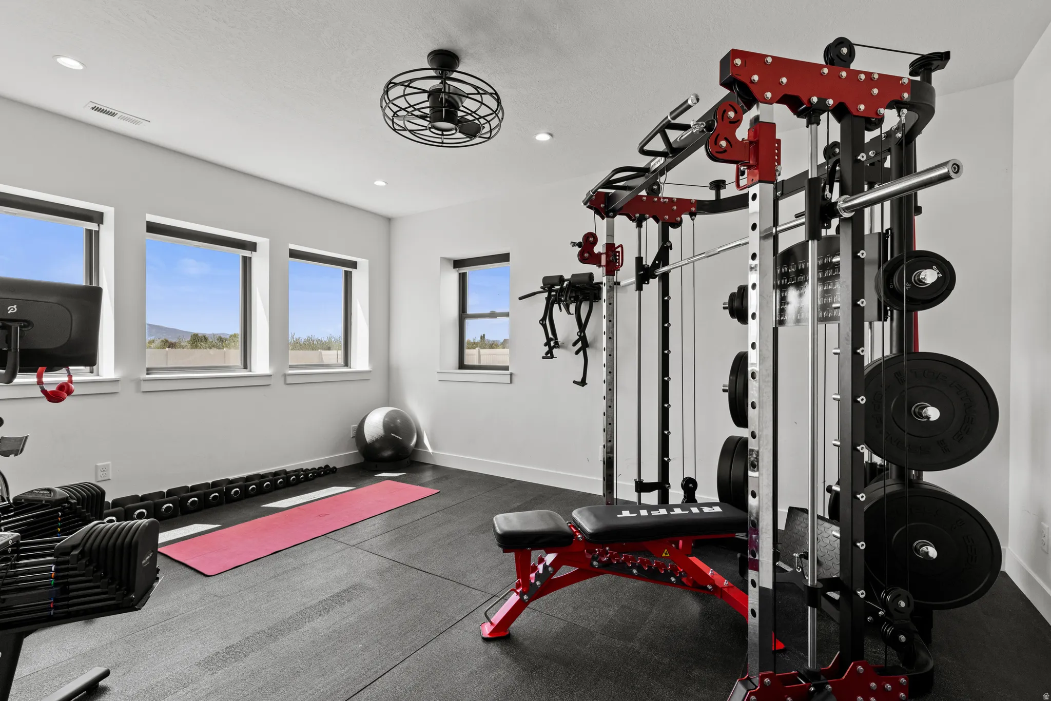 Dedicated fitness space featuring rubber flooring, recessed lighting, multiple large windows, and a ceiling fan
