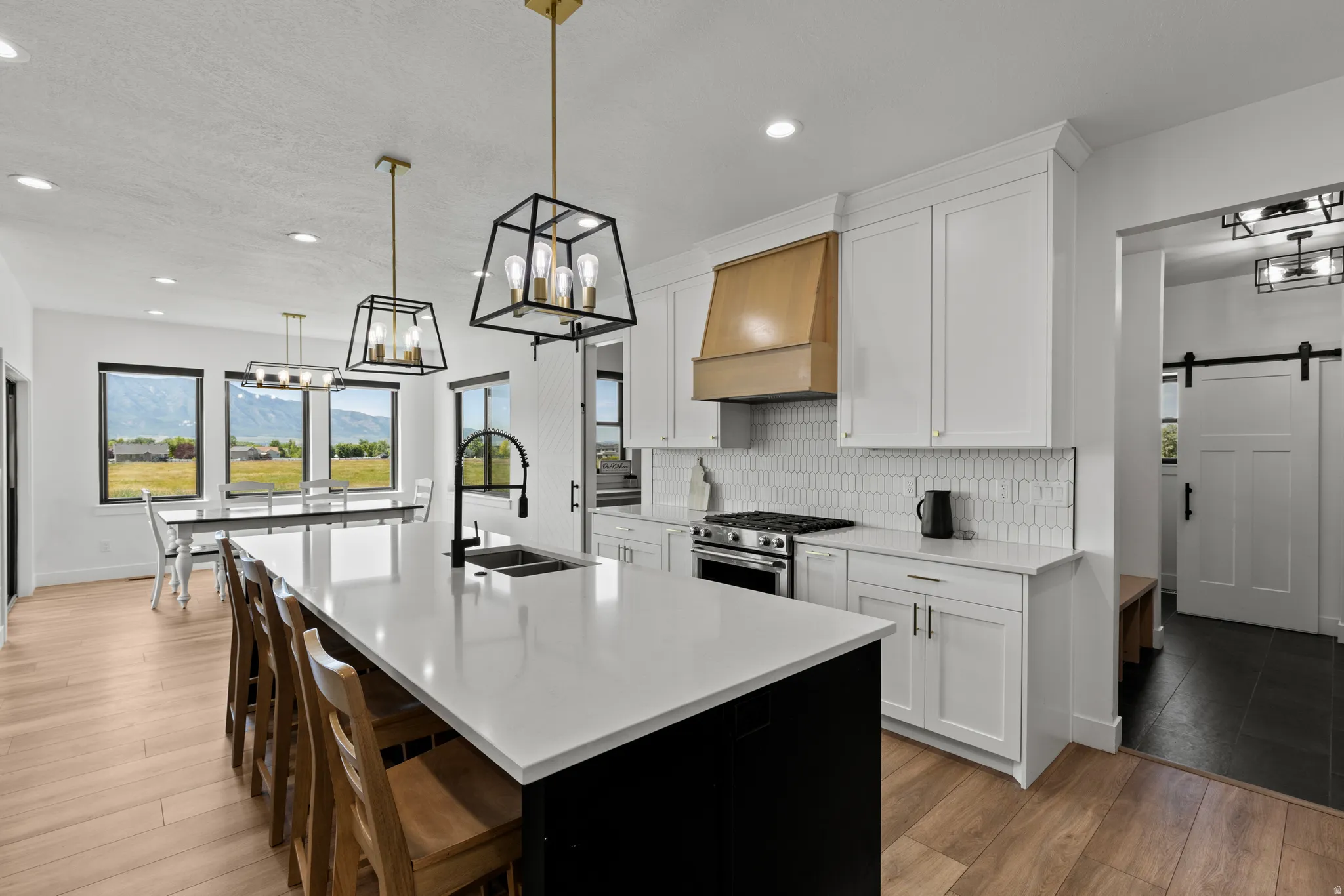 Expansive kitchen island with a white countertop and seating for four, complemented by two geometric pendant lights