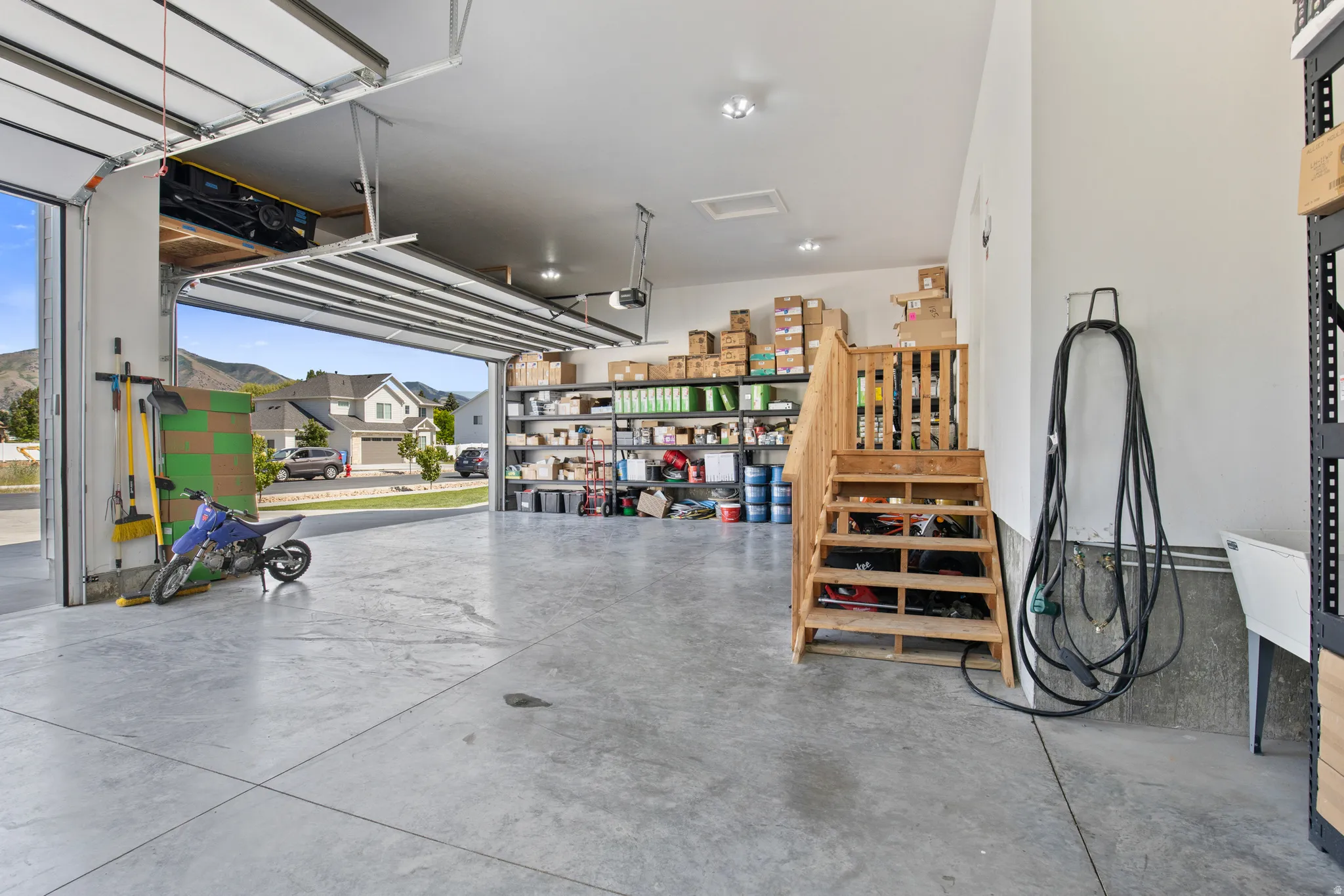 Spacious garage featuring a concrete floor, overhead lighting, and an open garage door