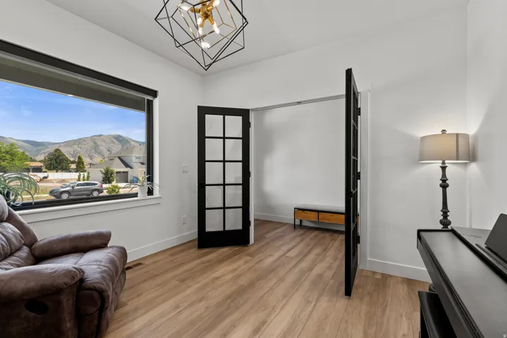 Spacious room featuring a large window, mountain scenery, light wood-finish flooring, and a modern geometric light fixture