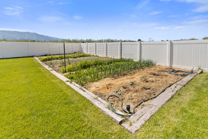 Expansive garden plot with wood-look borders, surrounded by a white privacy fence