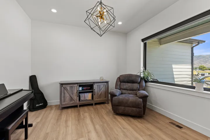 Bright room featuring a large horizontal window, wood-finish flooring, recessed lighting, a contemporary geometric light fixture, and white baseboards