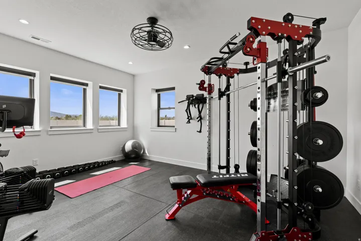 Dedicated fitness space featuring rubber flooring, recessed lighting, multiple large windows, and a ceiling fan