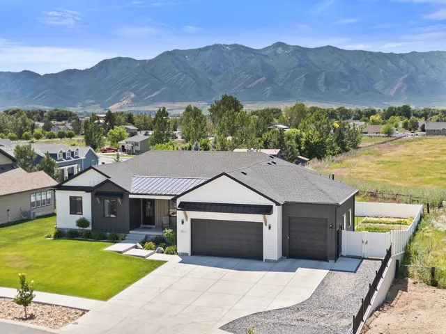 Modern farmhouse exterior with a combination of white siding and dark grey accents, featuring a two-car garage and an additional single-car garage