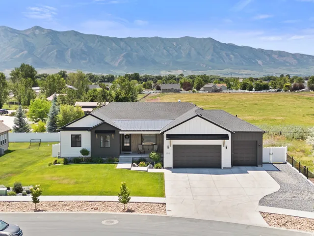 Contemporary single-story residence featuring a dark gray roofline and a two-tone exterior with white board and batten siding and dark gray horizontal siding