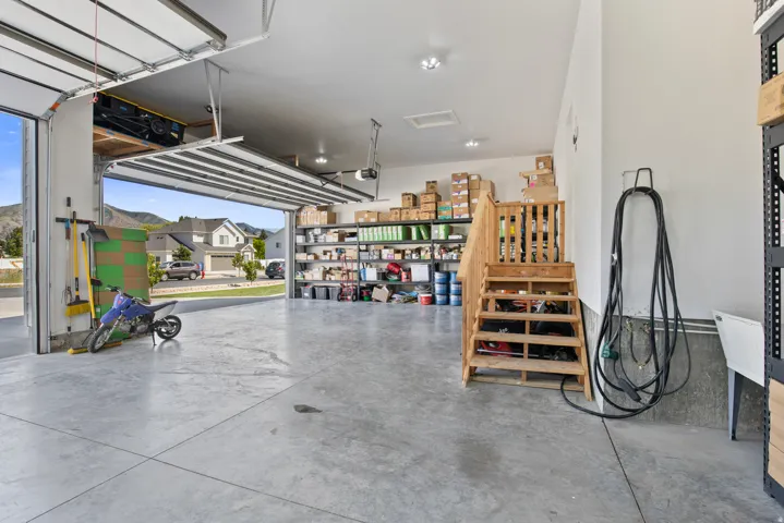 Spacious garage featuring a concrete floor, overhead lighting, and an open garage door