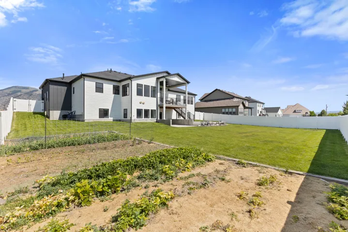 Expansive rear yard featuring a large grass lawn, dedicated garden area, and full privacy fencing