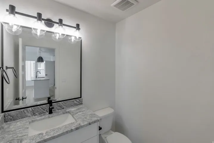 Bathroom vanity with a rectangular undermount sink, stone countertop, and matte black faucet