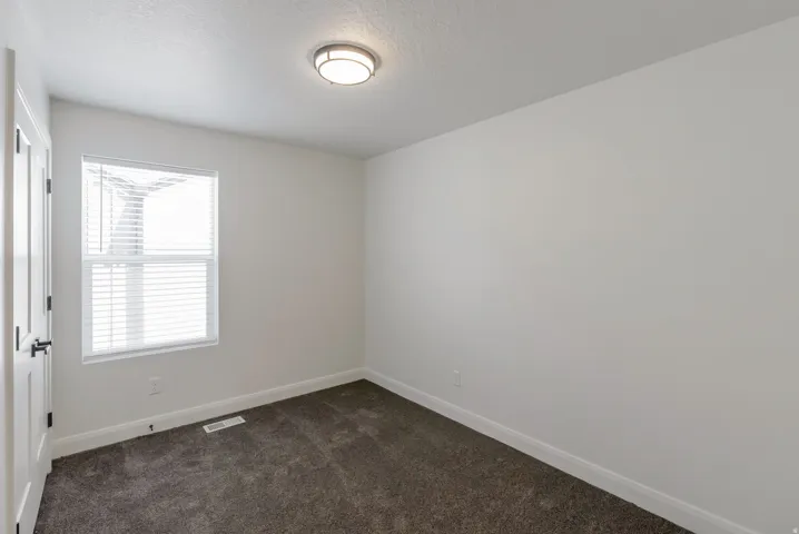Bright room featuring a window with white blinds, dark gray carpeting, and a flush mount ceiling light fixture
