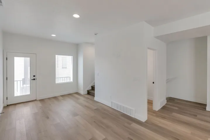 Open-concept living space with light wood-finish flooring, white walls, and recessed lighting