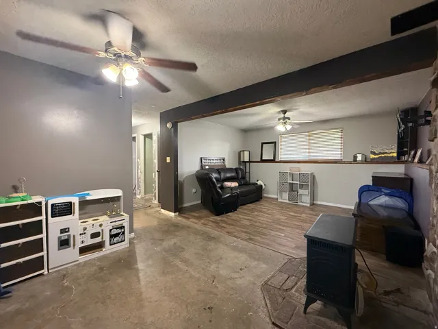 Spacious interior featuring wood-finish flooring, a ceiling fan with integrated lighting, and a prominent dark stained beam