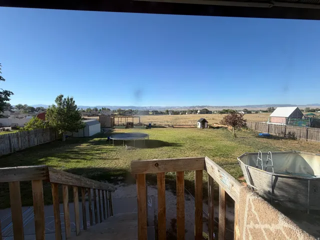 Expansive backyard featuring a partial wood privacy fence, a detached shed, and an above-ground pool