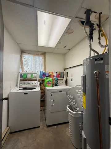 Utility room featuring a drop ceiling with integrated lighting, a window, and exposed piping