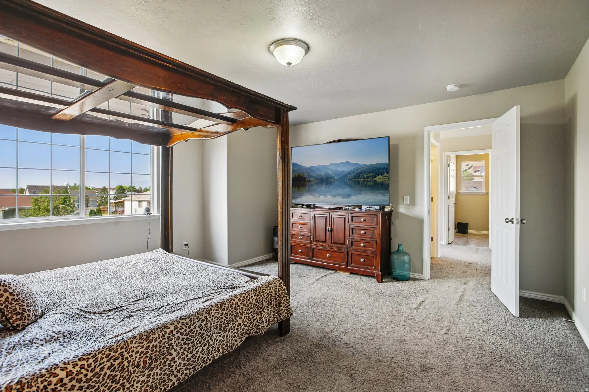Spacious room featuring broad windows with grid patterns, light-toned wall paint, and soft gray carpeting