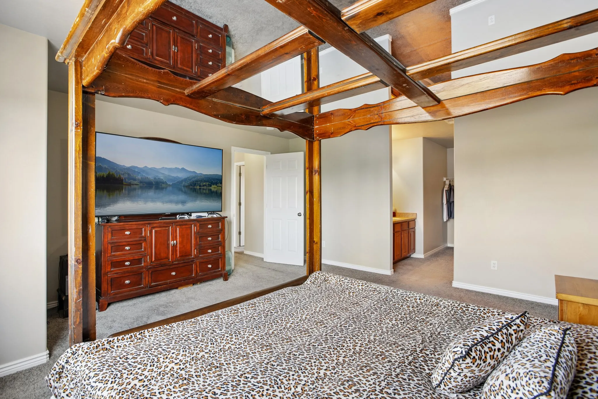 Spacious room featuring a four-poster wood-frame bed, carpeting, and light gray wall paint