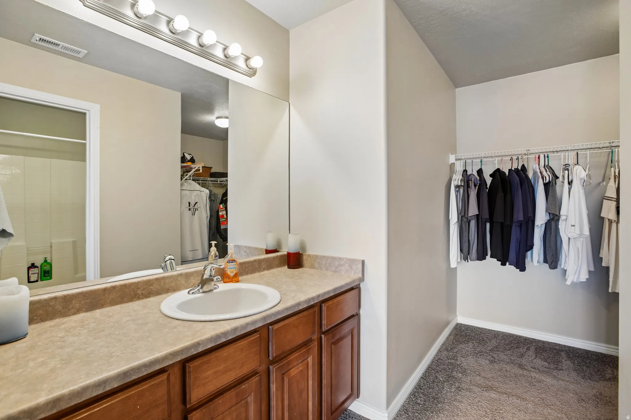 Bathroom vanity featuring a single basin sink, laminate countertop, and wood-finish cabinetry