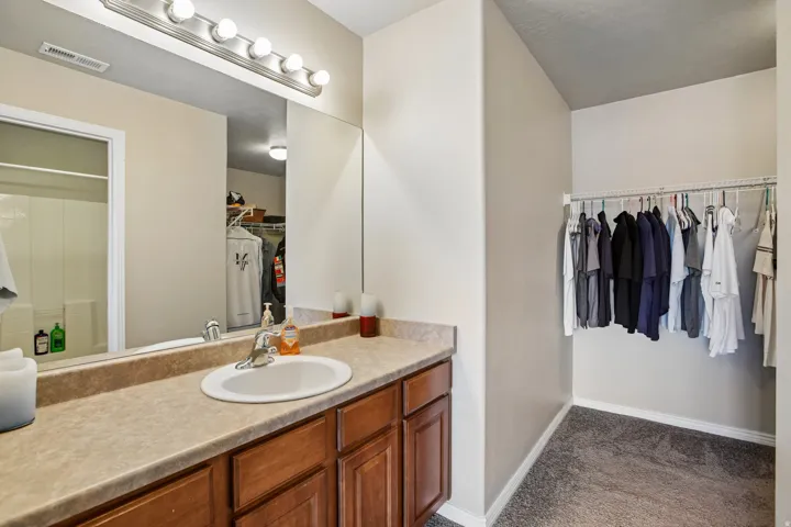 Bathroom vanity featuring a single basin sink, laminate countertop, and wood-finish cabinetry