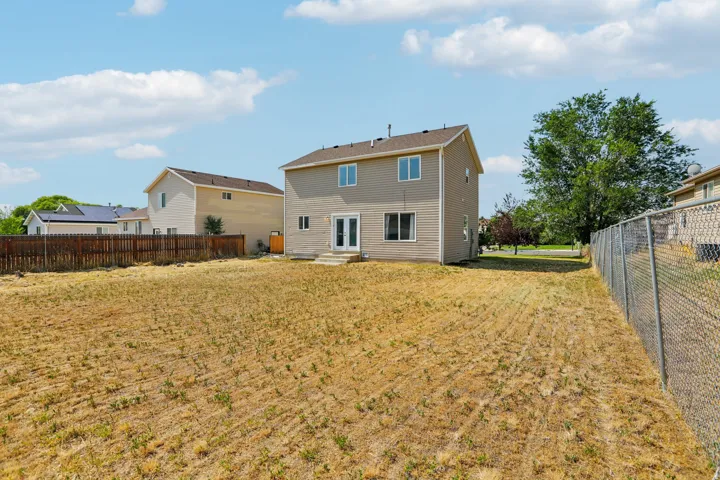 Expansive backyard featuring a two-story residence with light-colored siding and a brown roof