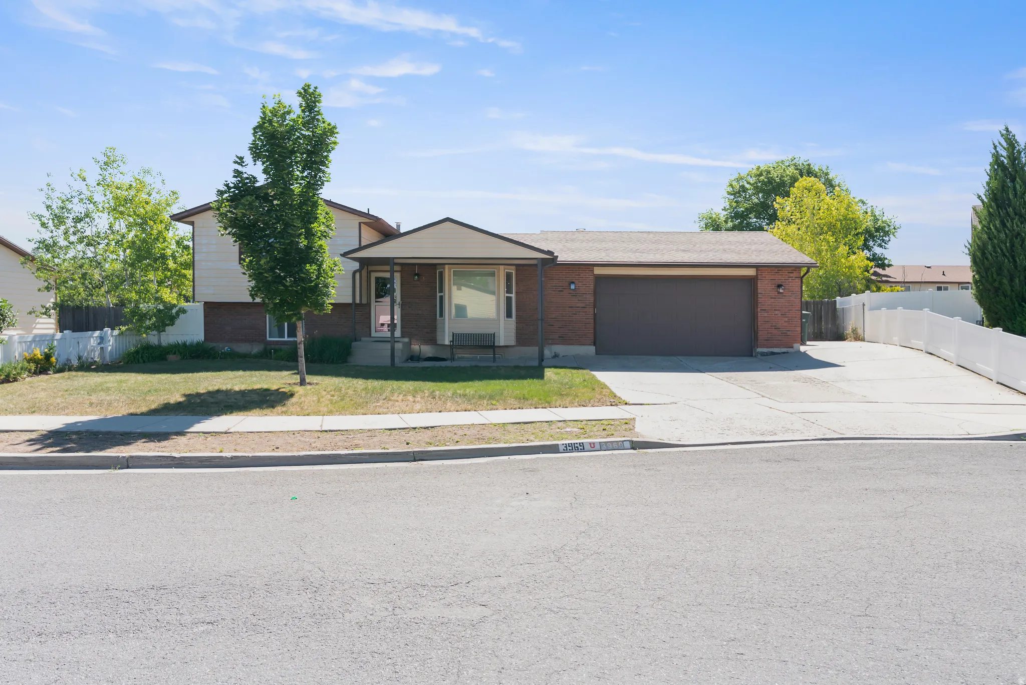 Split-level residence featuring a brick and siding exterior, an attached two-car garage, and a covered front entry