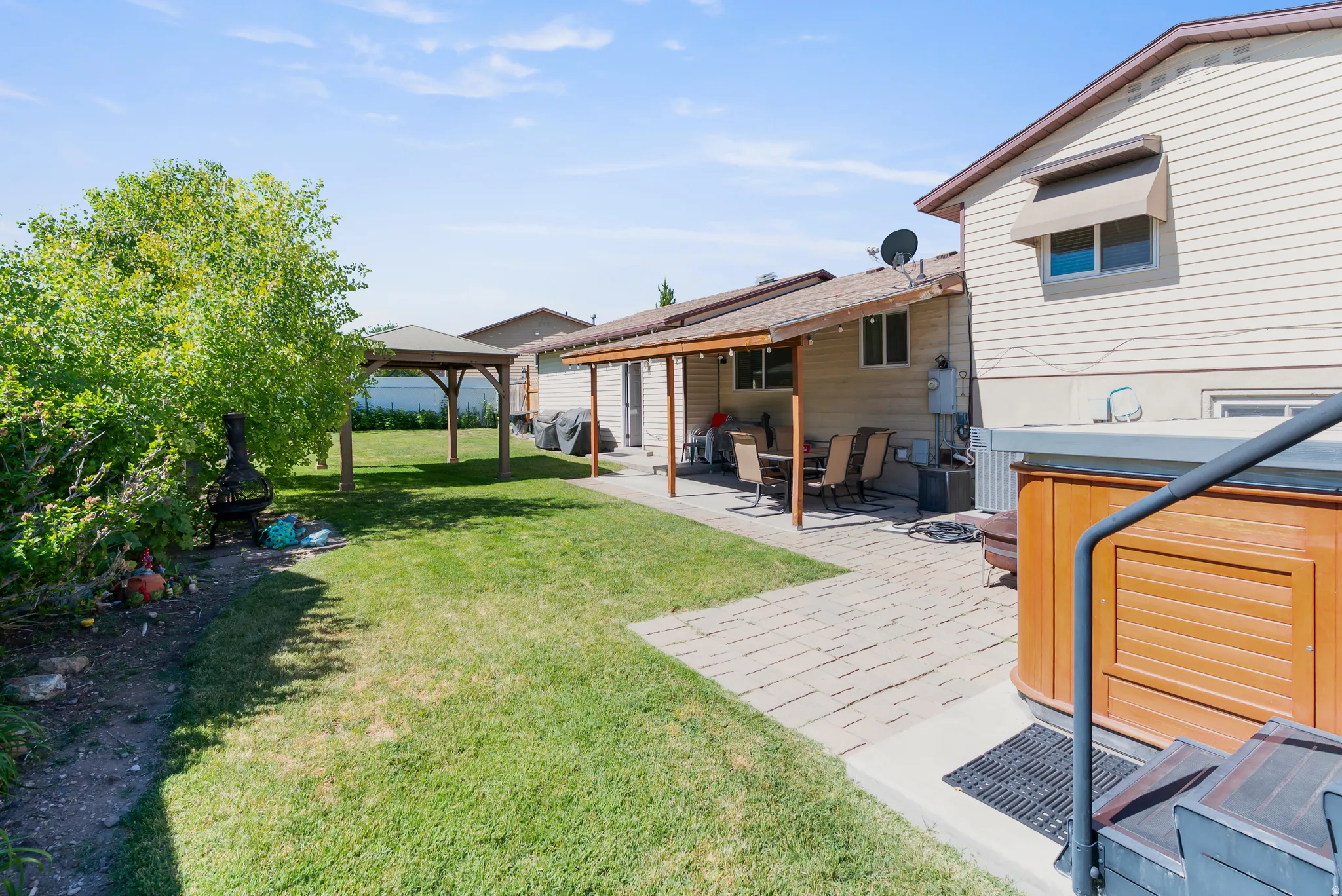 Backyard featuring a covered patio, paved walkway, and a freestanding wooden gazebo