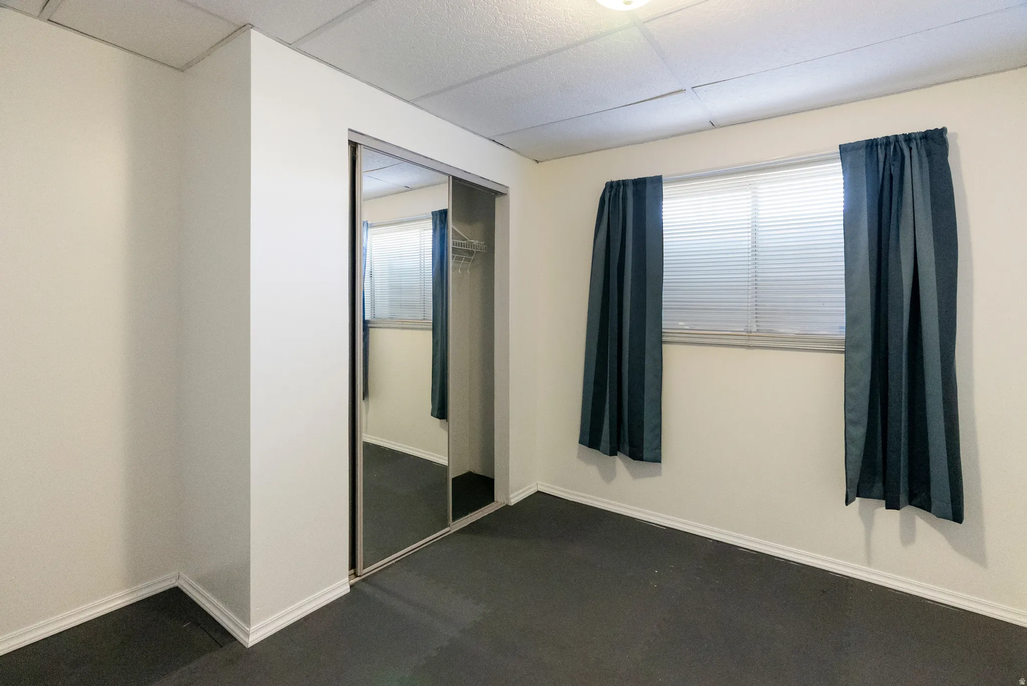 Room featuring a mirrored sliding closet door, a window with blinds, and recessed ceiling lighting
