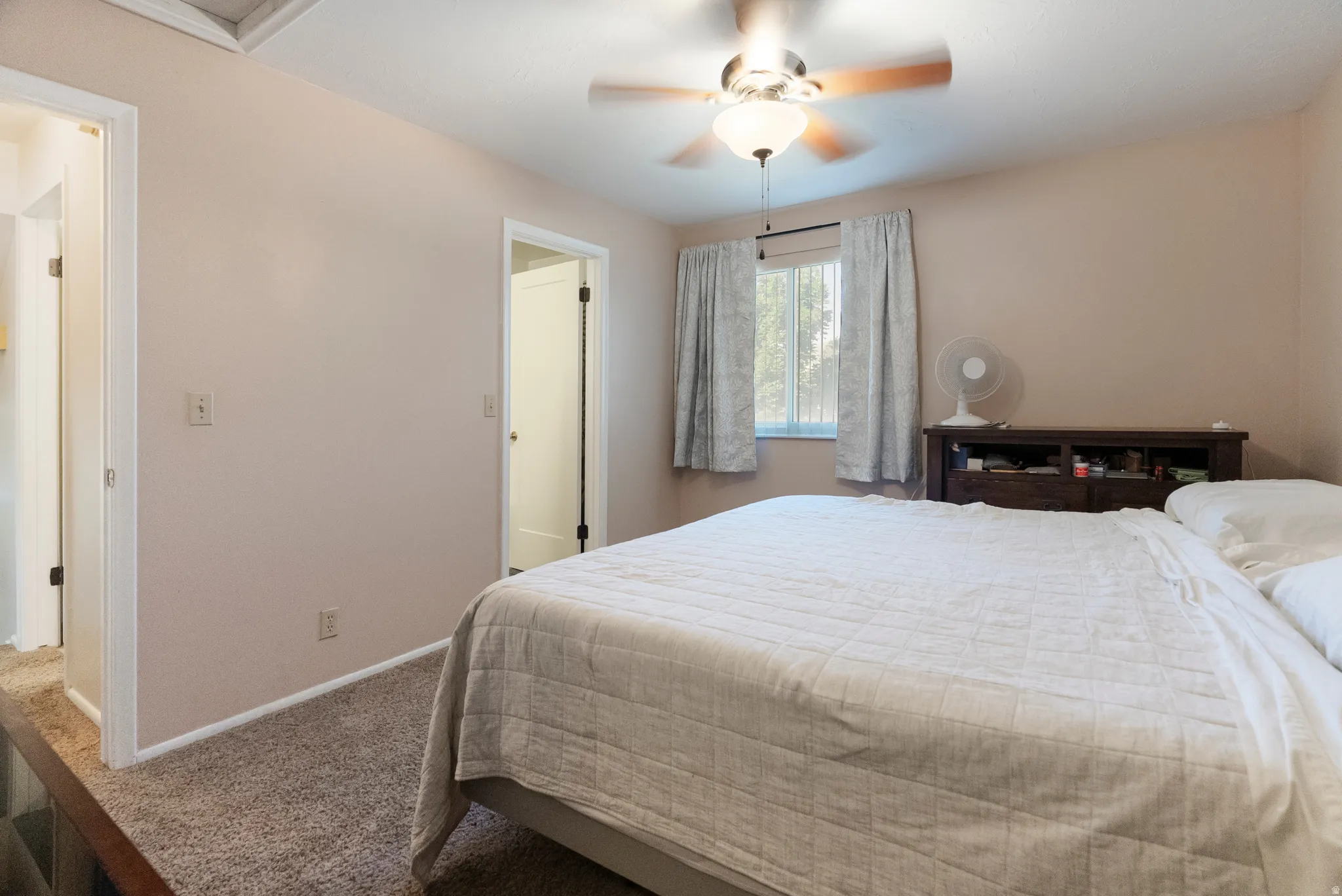 Carpeted room with a ceiling fan, a window, and two interior doorways