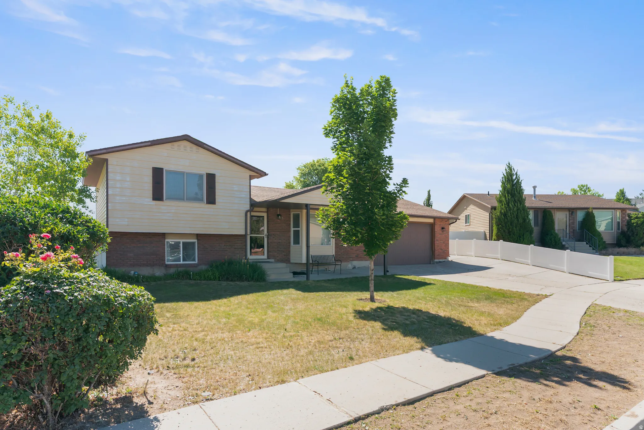 Split-level residence featuring a brick and siding exterior, an attached two-car garage, and a concrete driveway