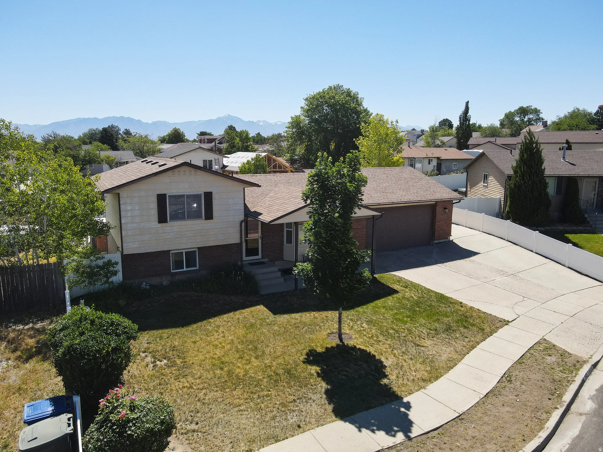 Split-level residence featuring a two-car garage, concrete driveway, and a front walkway