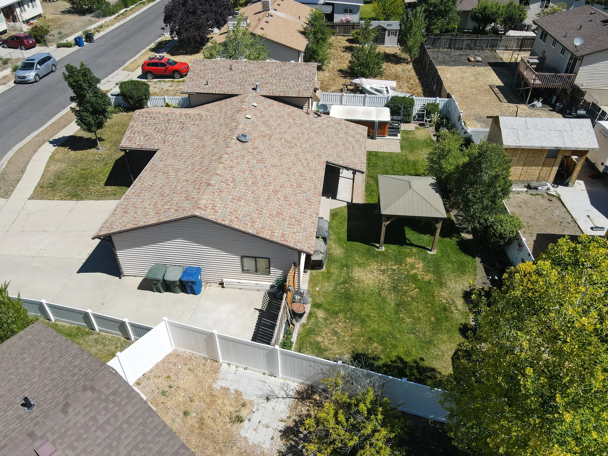 Expansive backyard featuring a green lawn, mature trees, and a covered gazebo
