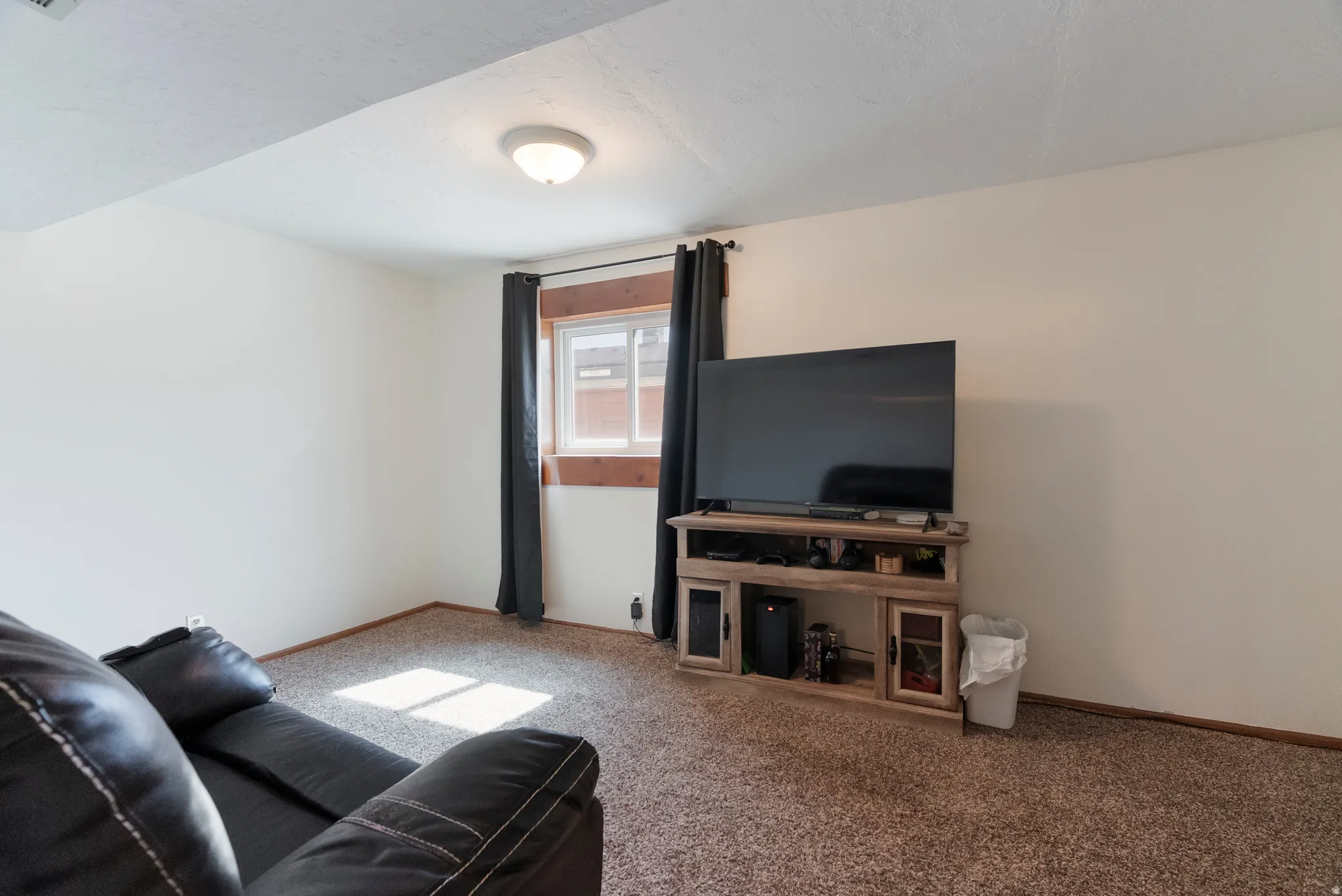 Carpeted room with neutral wall paint and a single window featuring wood trim
