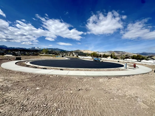 New construction development featuring a paved circular drive, concrete curbing, and sidewalks