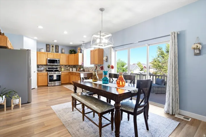Open-concept kitchen and dining area featuring wood-finish flooring, recessed lighting, and a sliding glass door to an outdoor deck