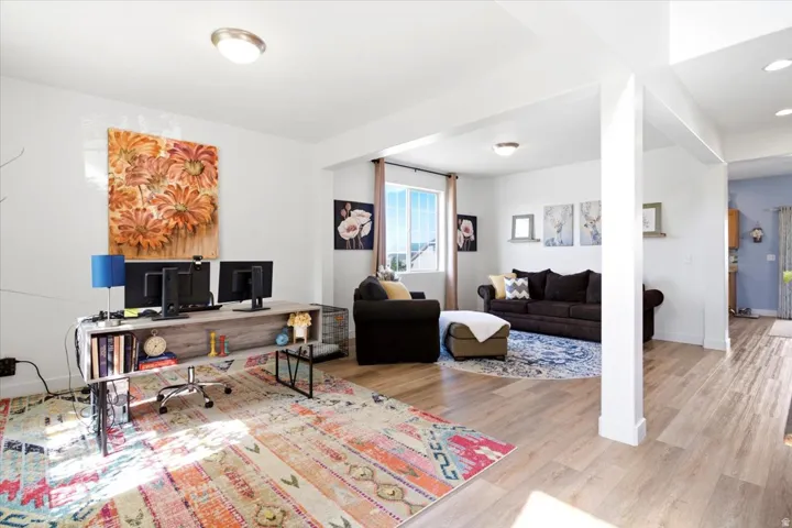Open-concept living area featuring light wood-finish flooring, white walls, and recessed lighting