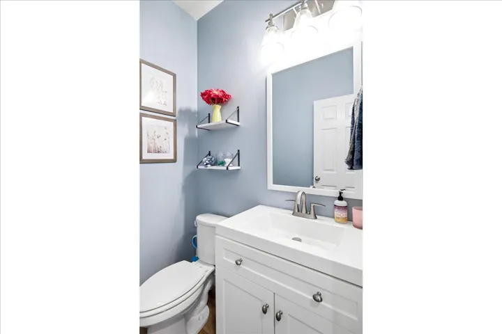 Bathroom featuring a white vanity with integrated sink, brushed nickel faucet, and a wall-mounted mirror