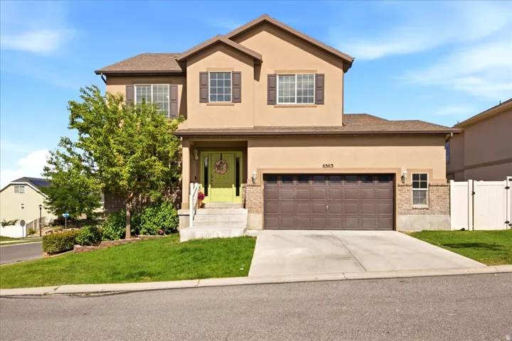 Two-story residence featuring a tan stucco exterior with brown accents and a two-car garage
