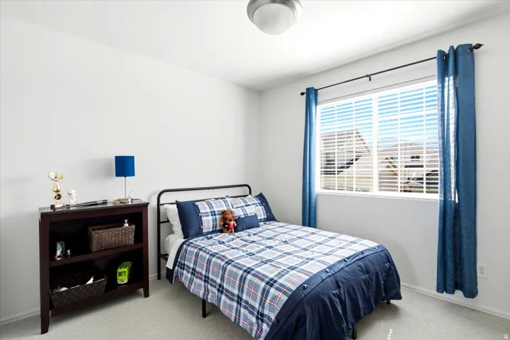 Bright room featuring a large window with blinds, light-colored carpeting, a contemporary flush-mount ceiling light, and white walls