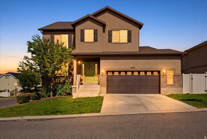 Two-story stucco residence featuring a two-car garage with a panel door, a green entry door, and dark shutters
