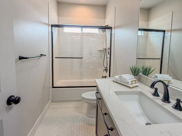 Contemporary bathroom featuring a single vanity with a white countertop and undermount sink, dark-stained cabinetry with matte black hardware, and tile flooring
