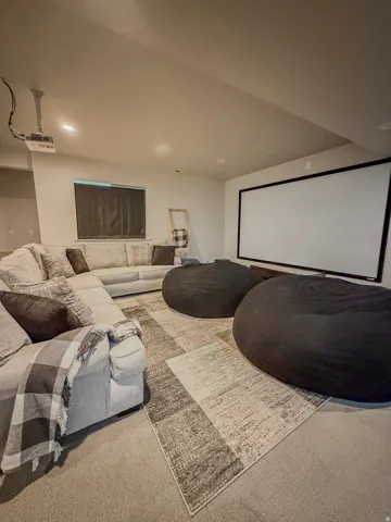 Media/Theater space featuring a wall-mounted projection screen, ceiling-mounted projector, and recessed lighting