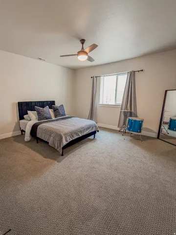 Carpeted room featuring a ceiling fan with integrated lighting, a window with a white frame, and light-colored walls