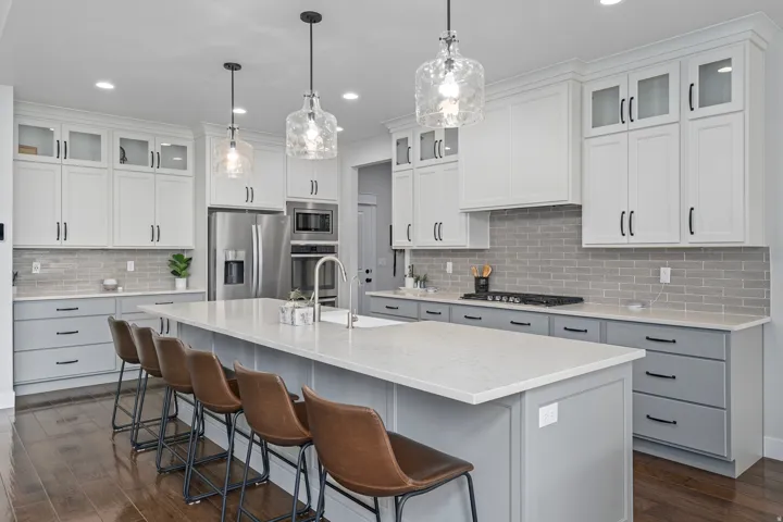 Kitchen featuring white cabinets, a breakfast bar, freestanding refrigerator, decorative backsplash, and light stone counters.