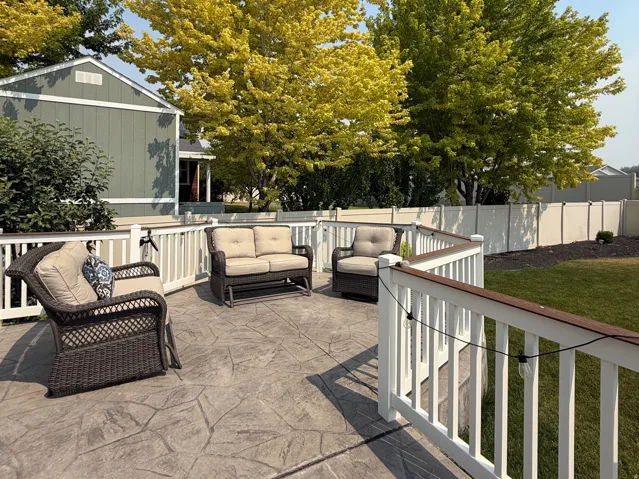 Expansive stamped concrete patio featuring a large white pergola and three sitting areas for entertaining.