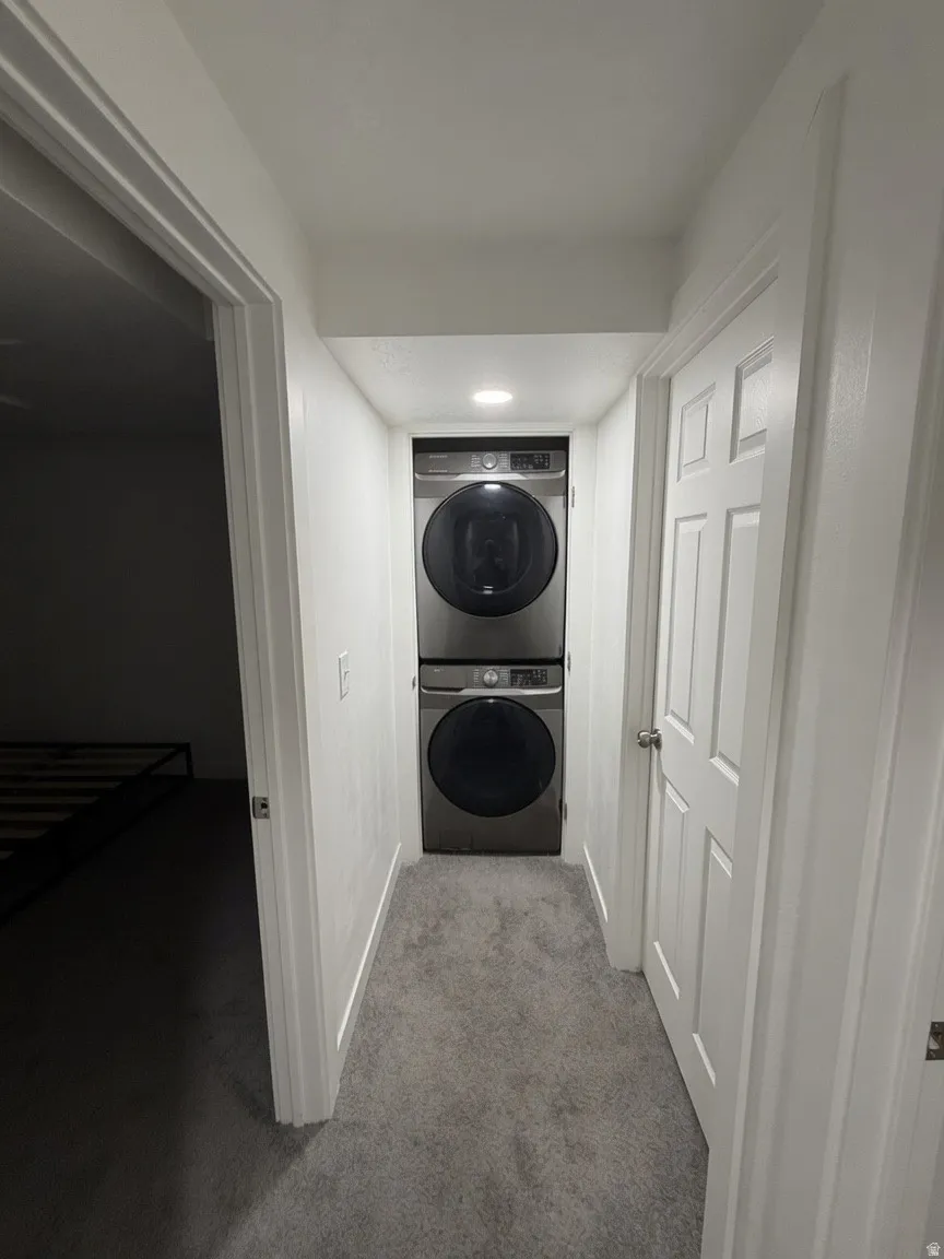 Dedicated laundry area featuring a stacked washer and dryer, recessed lighting, and light grey carpeting