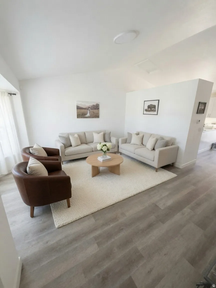 Spacious living area featuring light wood-finish flooring, a neutral color palette, and abundant natural light from a large window