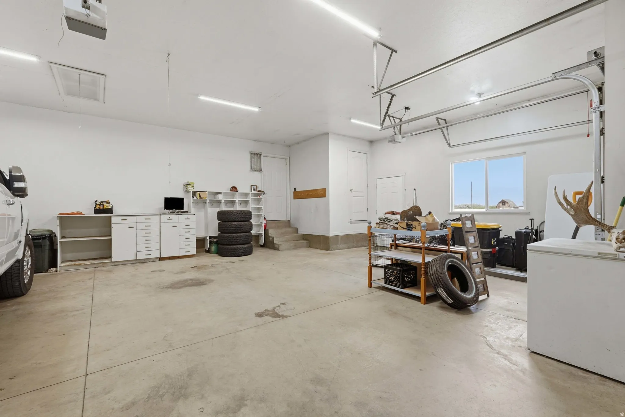 Spacious garage featuring a concrete floor, multiple fluorescent light fixtures, and white walls