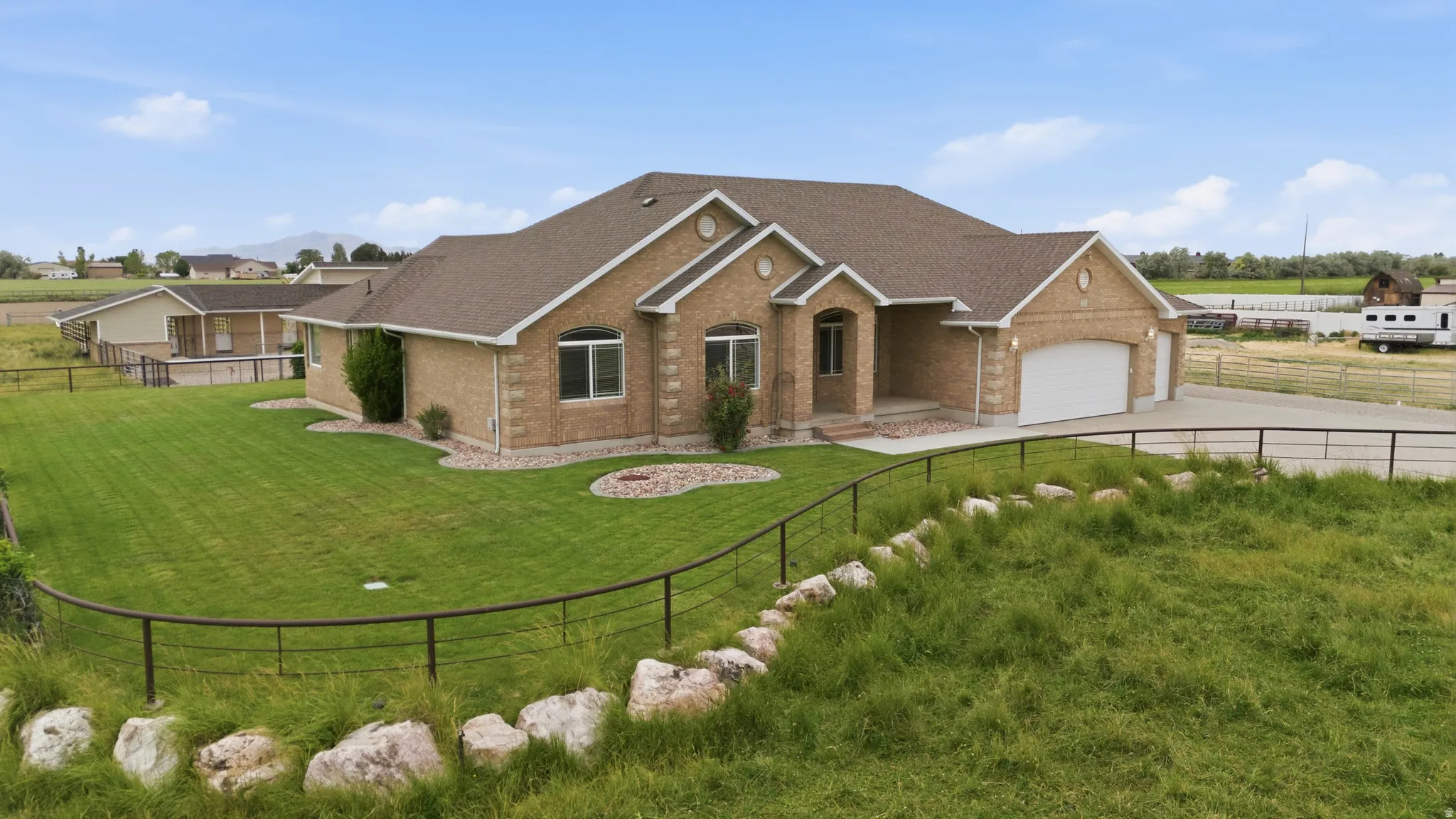 Brick exterior residence featuring an attached two-car garage, front yard landscaping, and a fenced perimeter