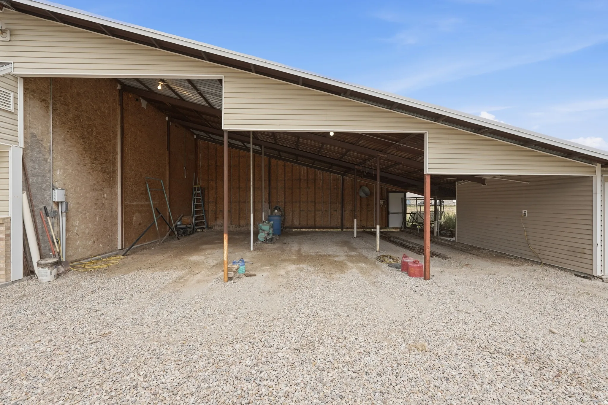 Expansive covered structure featuring a gravel floor, metal roofing, and exposed wood siding